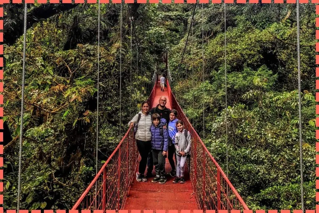 Foto de Familia Watson con el puente rojo del bosque nuboso de Monteverde rodeados de abundante vegetación. 