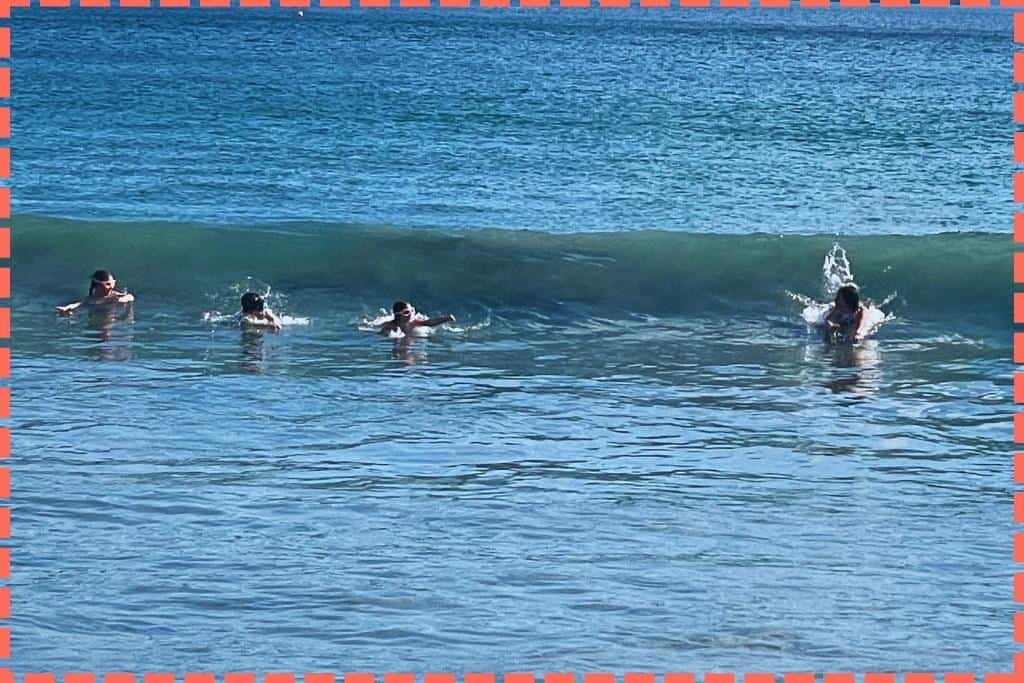 Una mamá y tres niños disfrutan barrenando olas en Playa Danta, en las pintorescas playas de Costa Rica.