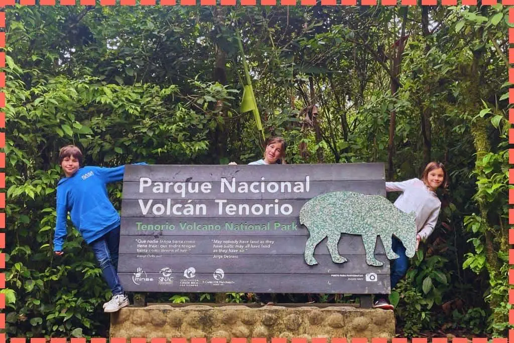 Tres niños detrás del cartel del Parque Nacional Volcán Tenorio en Costa Rica.