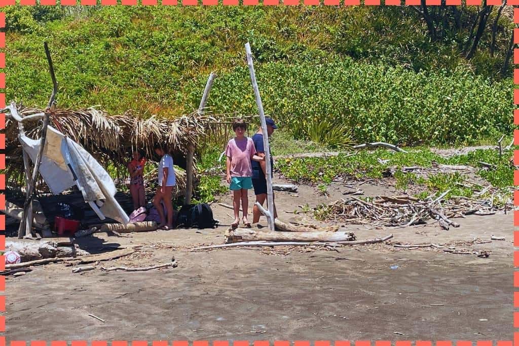 Familia refugiada en una cabaña rústica hecha de palmeras secas y palos en Playa Azul, Costa Rica.