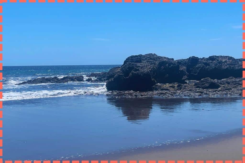 Rocas de arena negra destacando en la serena Playa Azul de Costa Rica