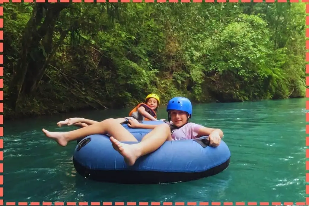 Sofi y Vicky sonríen mientras flotan en un tubing en el río Celeste, rodeadas del exuberante paisaje característico de Costa Rica.