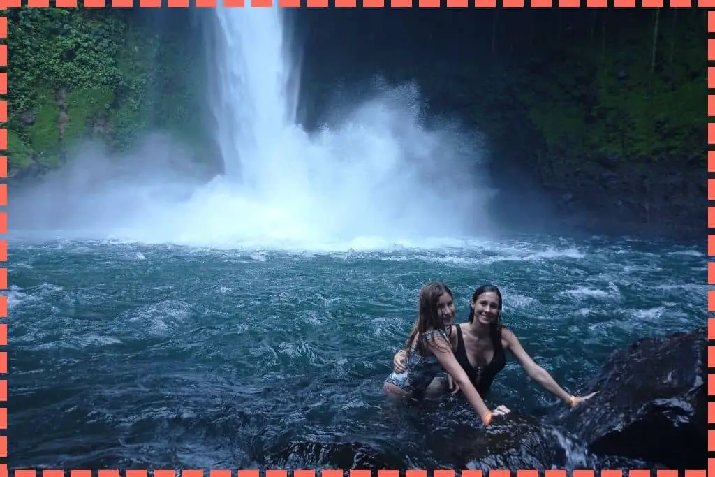 Tere Watson junto a su hija disfrutan del río con la cascada de La Fortuna de fondo. 