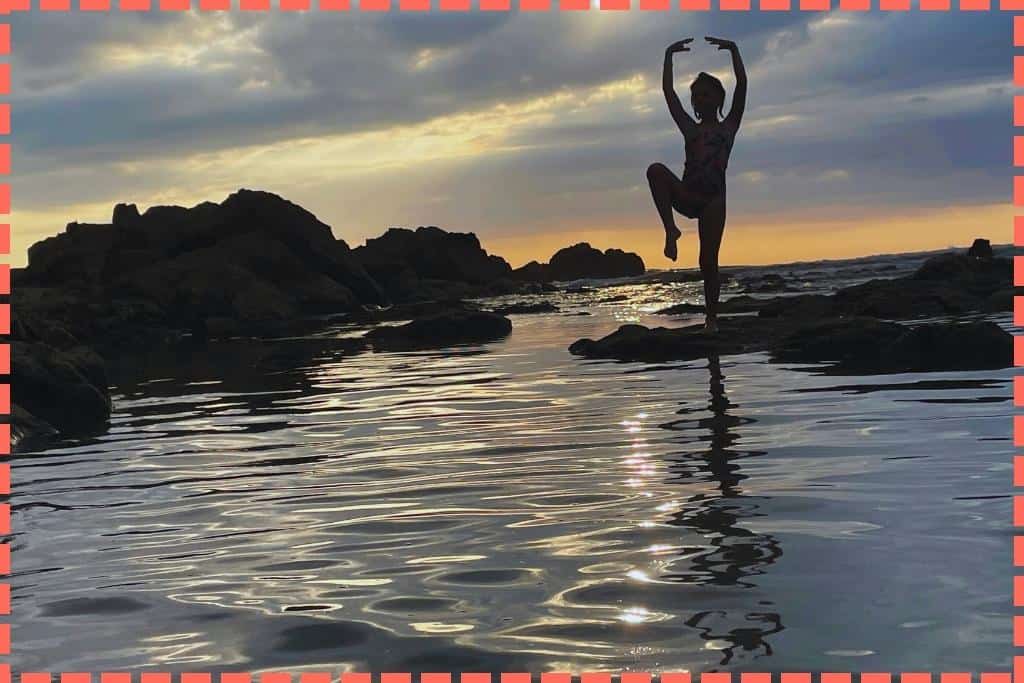Vicky haciendo equilibro en una roca del mar, al atardecer. En Playa Mar Azul.
