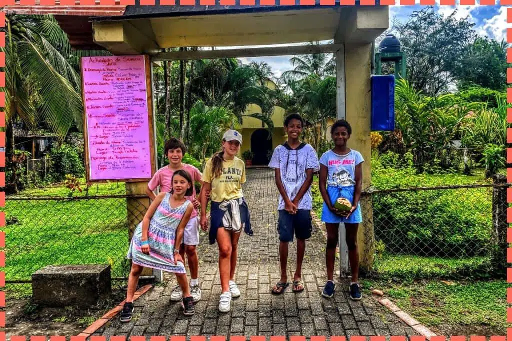 Niños visitantes y locales reunidos frente a la pintoresca iglesia del pueblo de Tortuguero, Costa Rica, reflejando la comunidad y el patrimonio local.