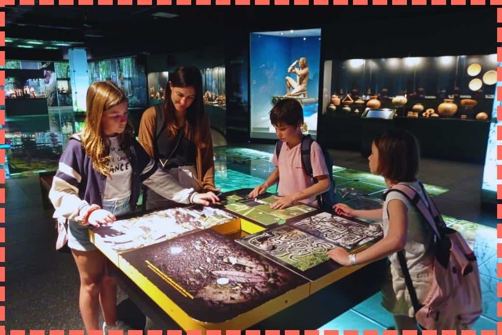 Tere Watson y sus tres hijos participando en actividades interactivas en el Museo del Jade en San José, Costa Rica, concentrados en una misma mesa de actividades donde cada uno disfruta de su propia experiencia de aprendizaje, destacando la diversión familiar en uno de los principales puntos de interés de la ciudad.