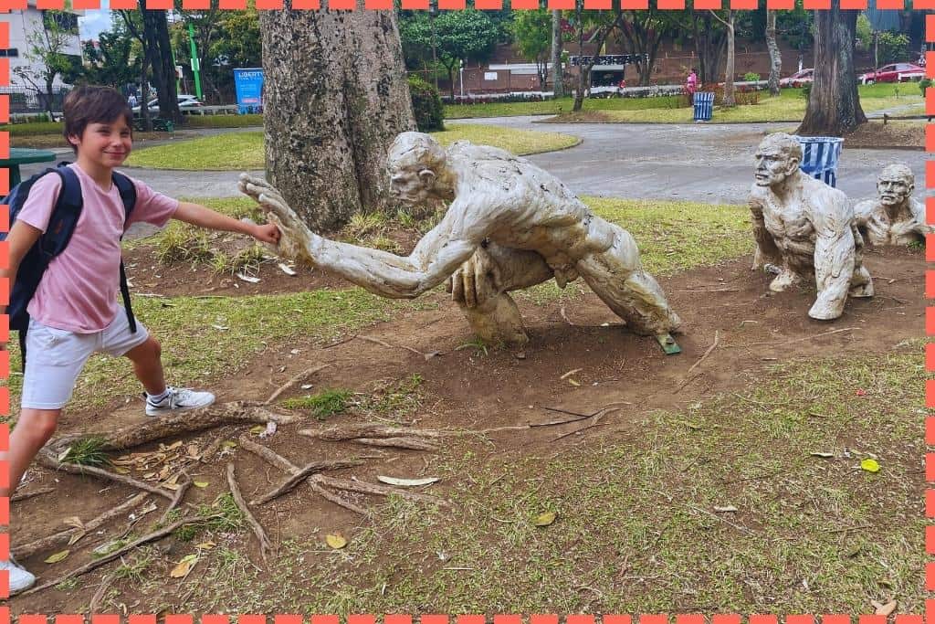 Ian, el hijo de Tere Watson, interactuando con la escultura 'Nuevo Paradigma' en el Parque Nacional de San José, Costa Rica. Este momento captura su curiosidad y diversión mientras explora esta obra artística, que simboliza superación y esfuerzo en un entorno urbano y cultural
