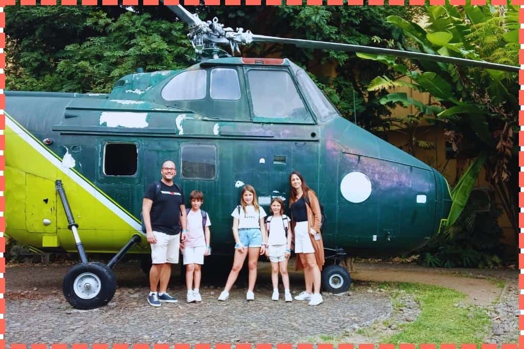 La familia Watson de pie frente a un helicóptero en el Museo de los Niños, mostrando entusiasmo y curiosidad mientras exploran esta fascinante exhibición.