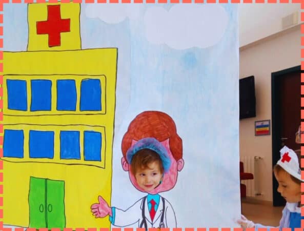 Ian Y Sofi de pequeños poniendo la cabea en un cartel con un hospital dibujado.
