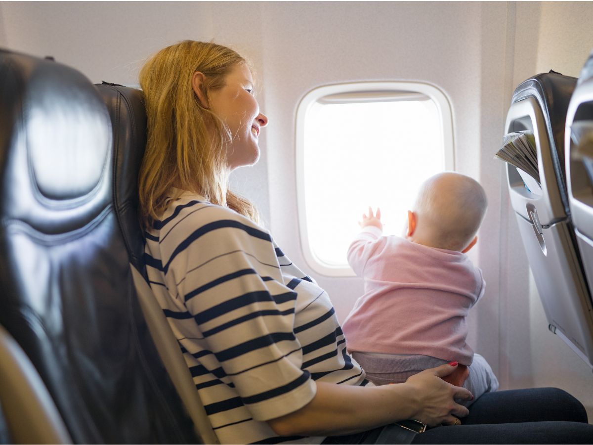 Mamá Volando tranquila y feliz con su bebé. Mostrando que se puede viajar con bebés en avión sin pasar estrés.